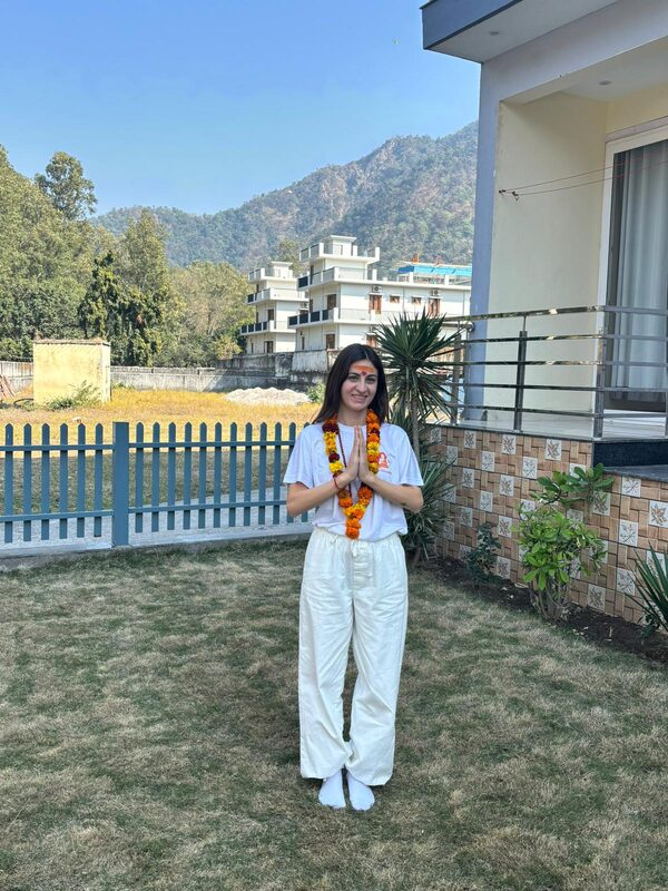 Cristina in posizione namaste con ghirlanda di fiori in India