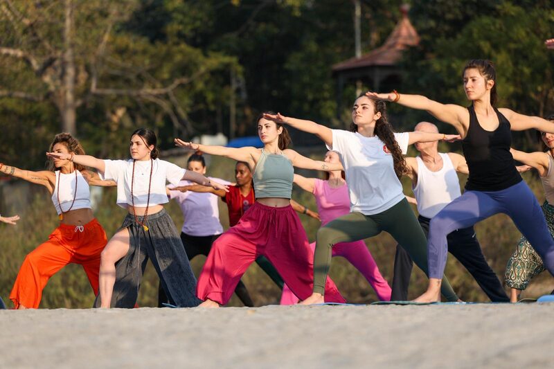 Pratica di gruppo all'aperto in India - posizione del guerriero